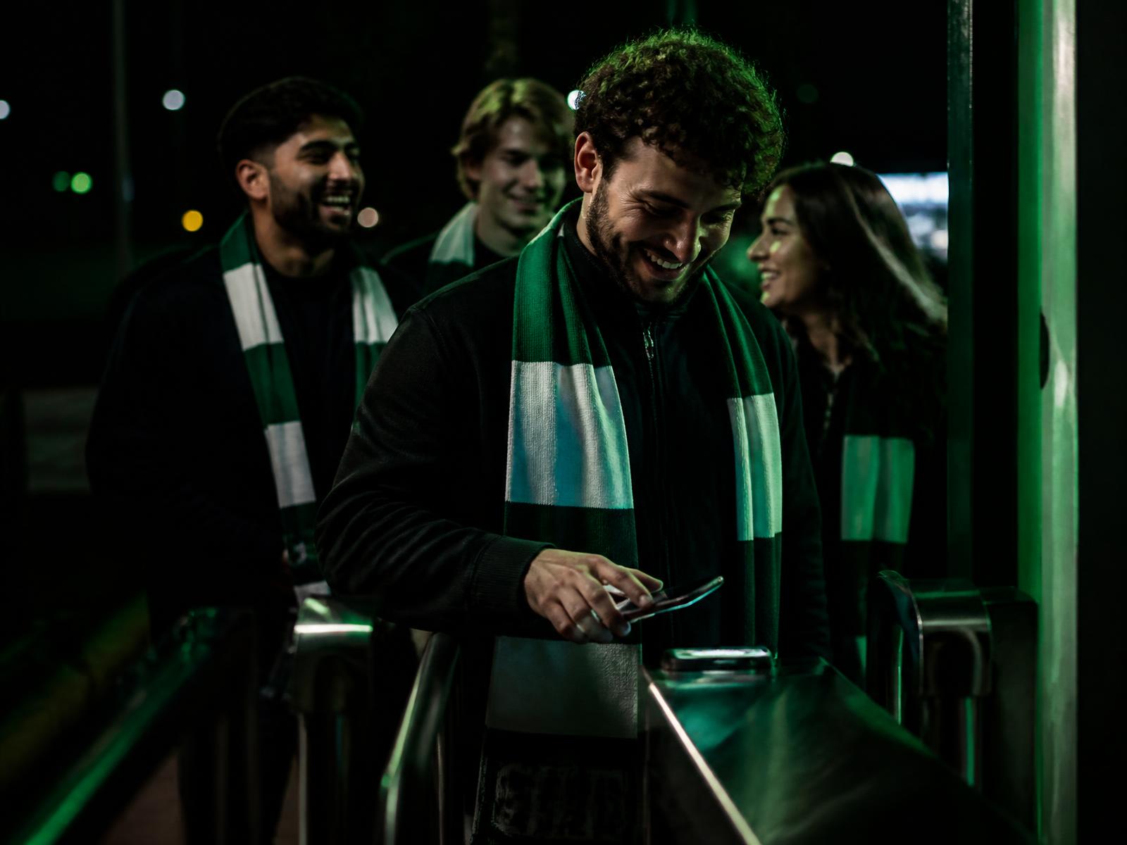 Ein Fan hält nachts ein Handyticket an ein Drehkreuz-Lesegerät im Stadion
